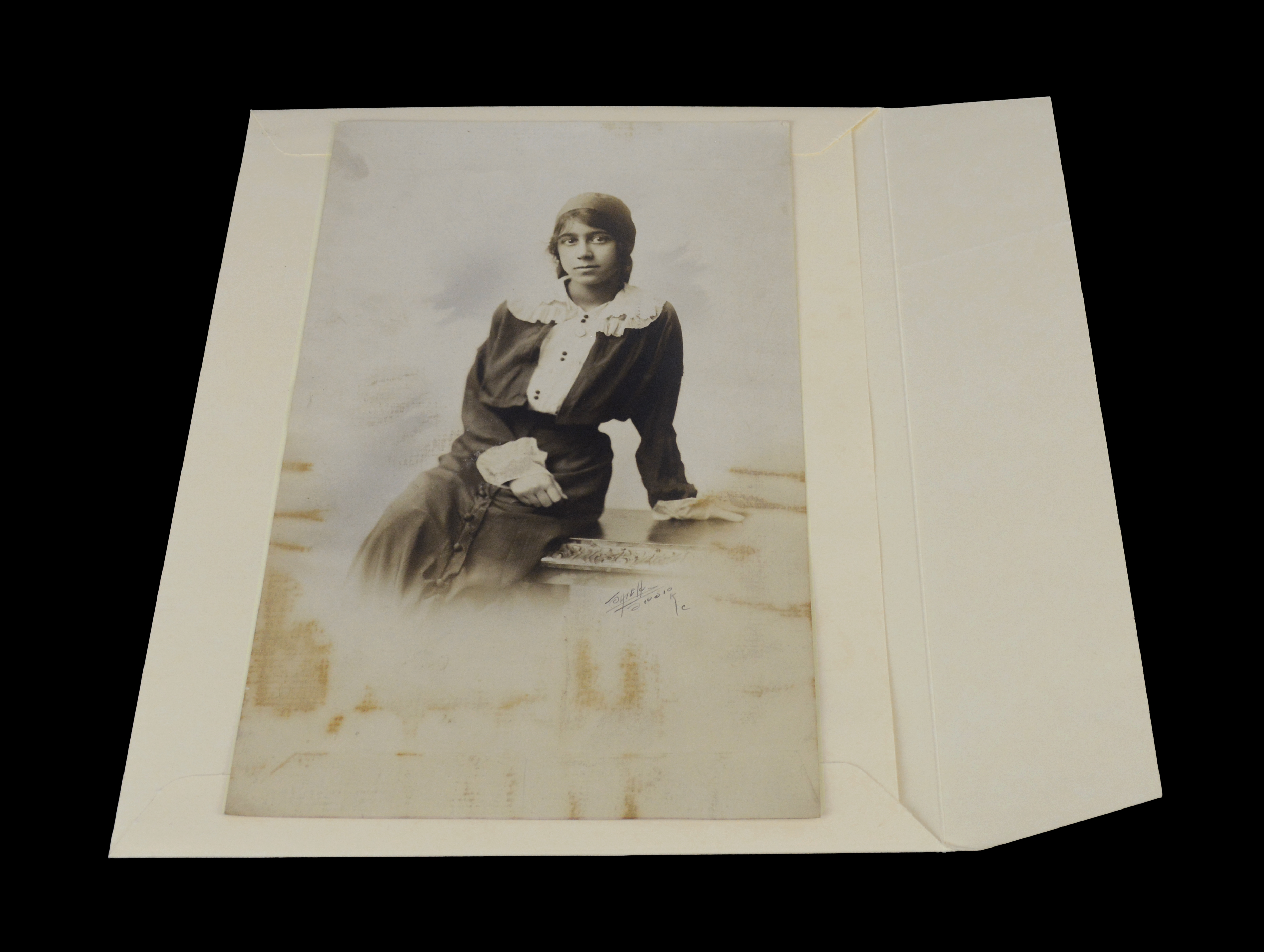 Vintage sepia photo of young woman atop acid-free archival buffered envelope with flap on long edge, no adhesive on flap